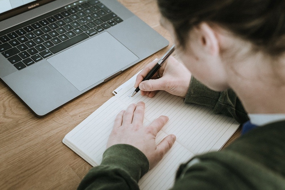 A woman writing an outline before starting to type her self-published novel