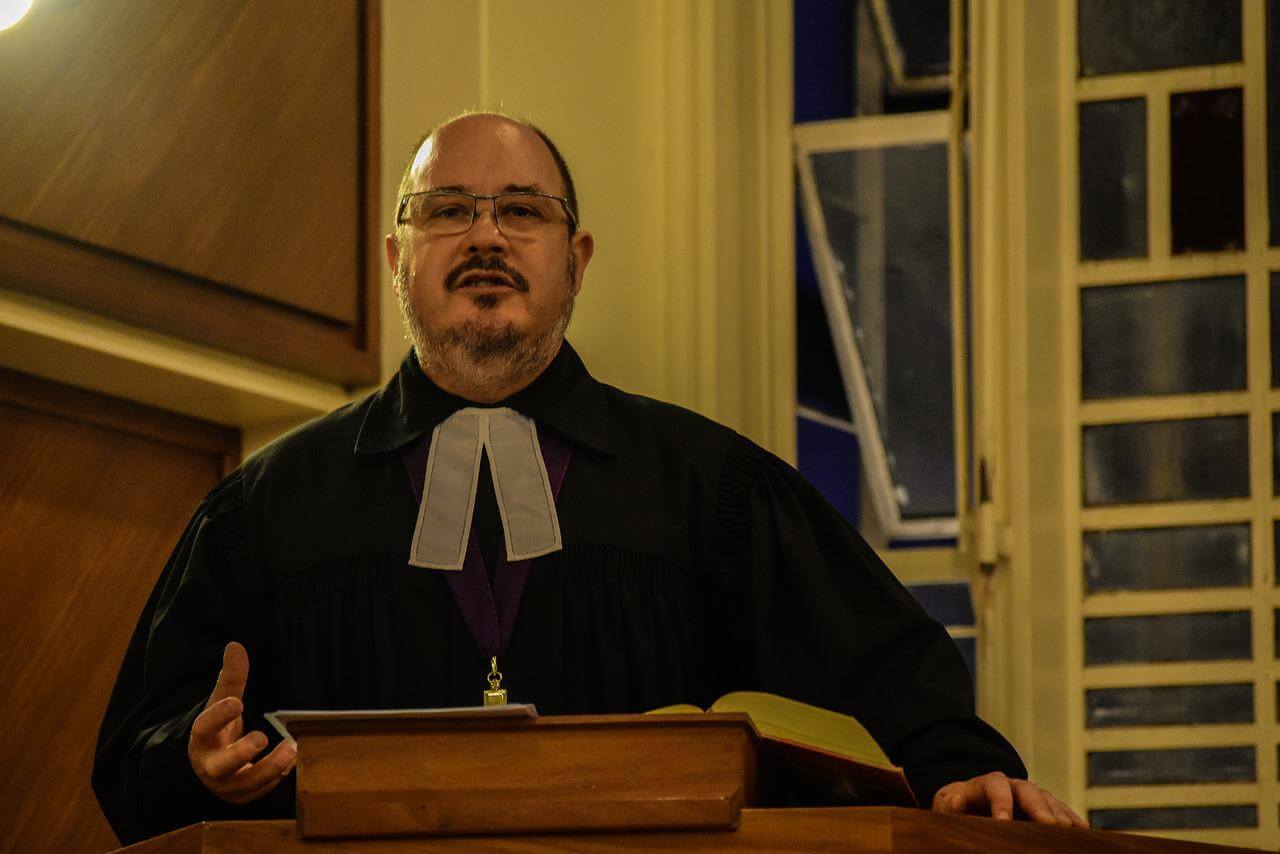 A pastor delivering a sermon with self-published sermons from a vanity press
