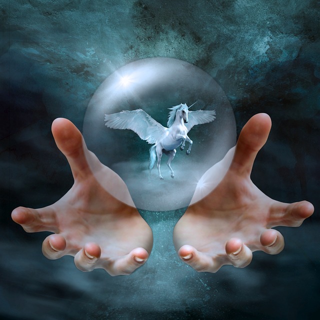 Hands of a self-publishing author holding a globe with a unicorn to represent creating a fantasy story. 